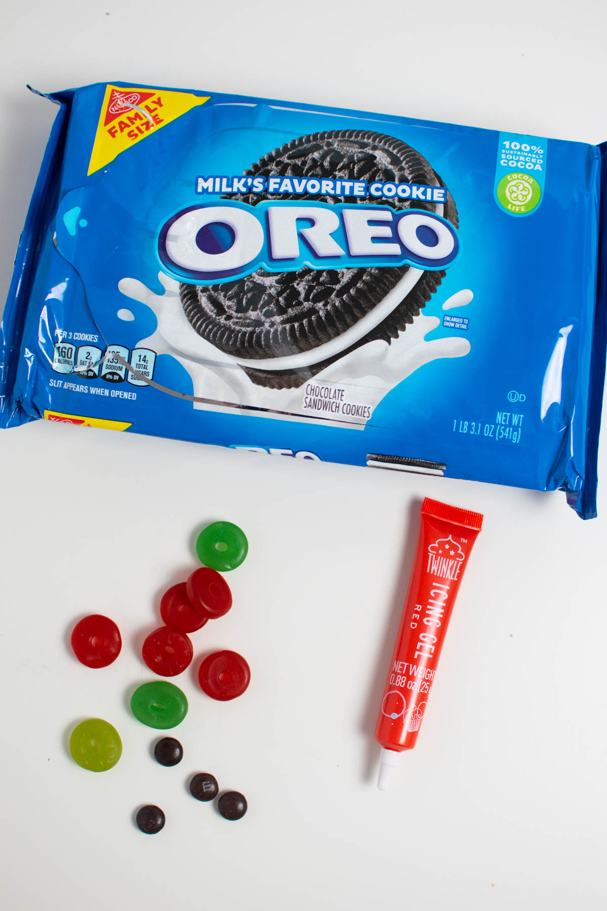 Oreo eyeball ingredients on white table including candies, red icing gel, and package of Oreos.