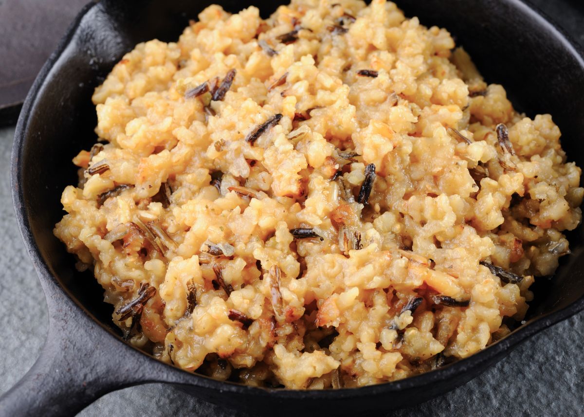 Creamy wild rice in a large black skillet on gray background.