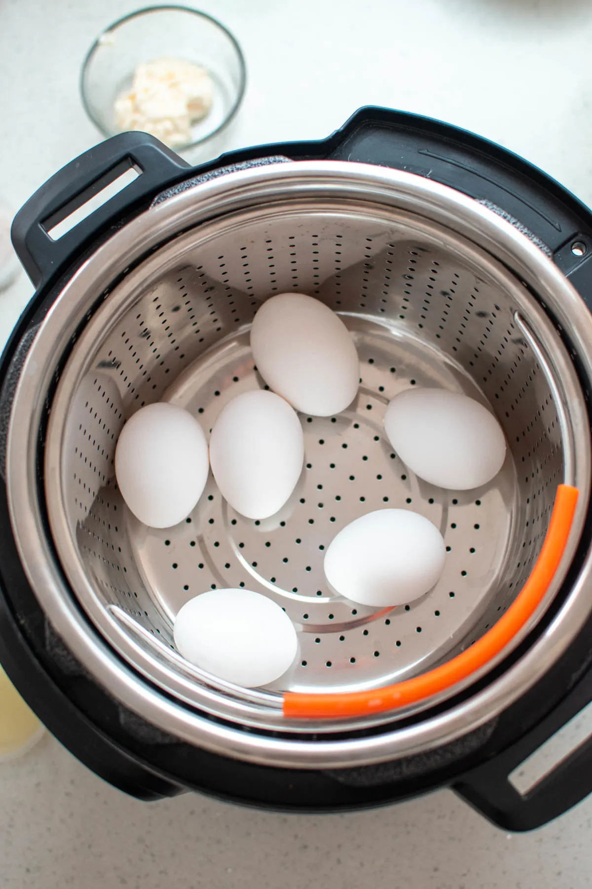 Six eggs on trivet in Instant Pot insert all on quartz countertop.