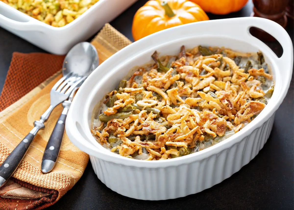 Large white casserole dish filled with green bean casserole with crispy onions on top.