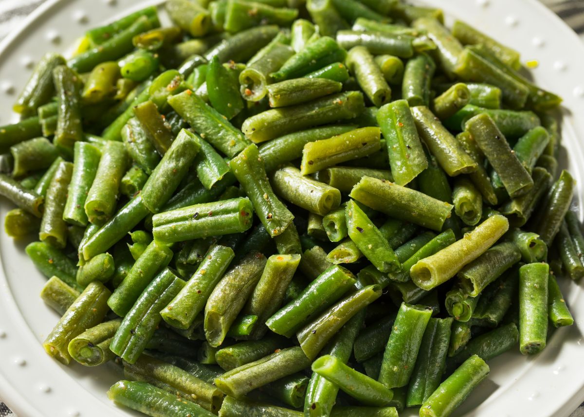 Large platter of bright green cut green beans lightly cooked with seasonings.