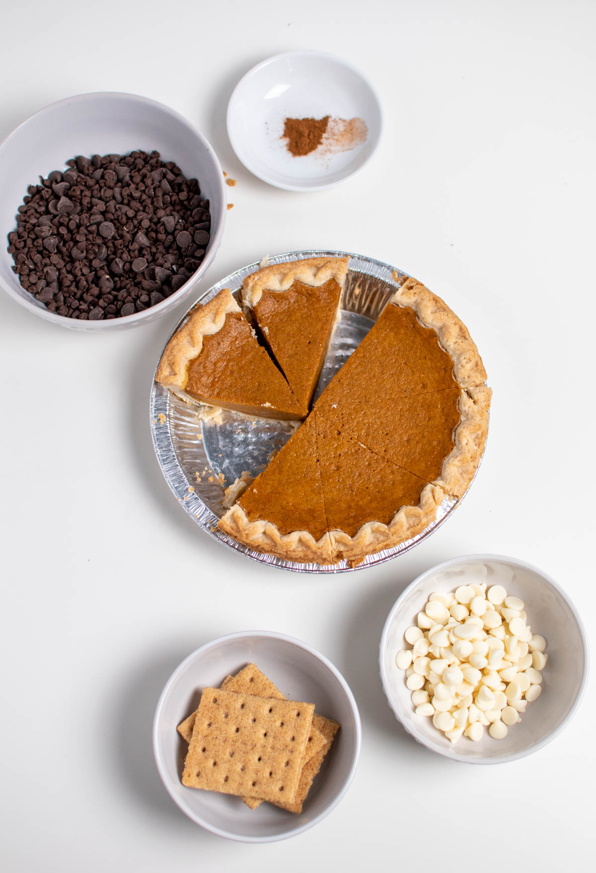Leftover pumpkin pie truffle ingredients on table including chocolate chips, graham crackers, and pumpkin pie.