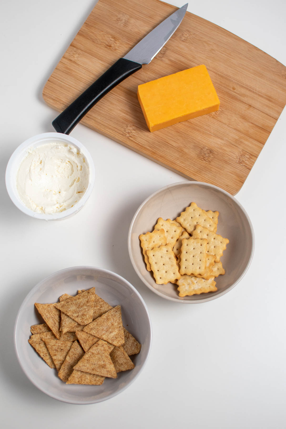 Pumpkin pie appetizer ingredients on table including cheese, crackers, and cream cheese.