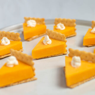 Pumpkin pie cheese crackers with cream cheese on gray cake stand.