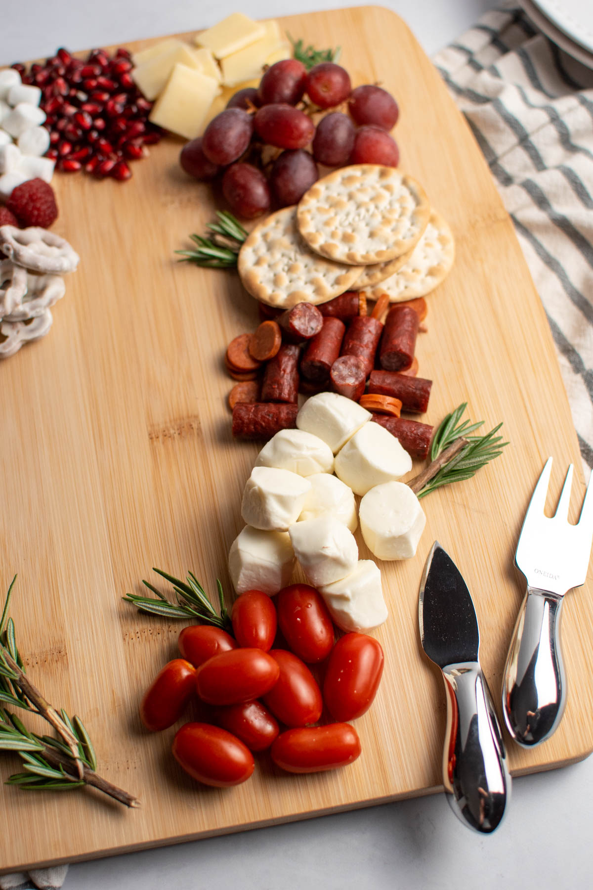 Christmas charcuterie board with red and white foods and fresh rosemary.