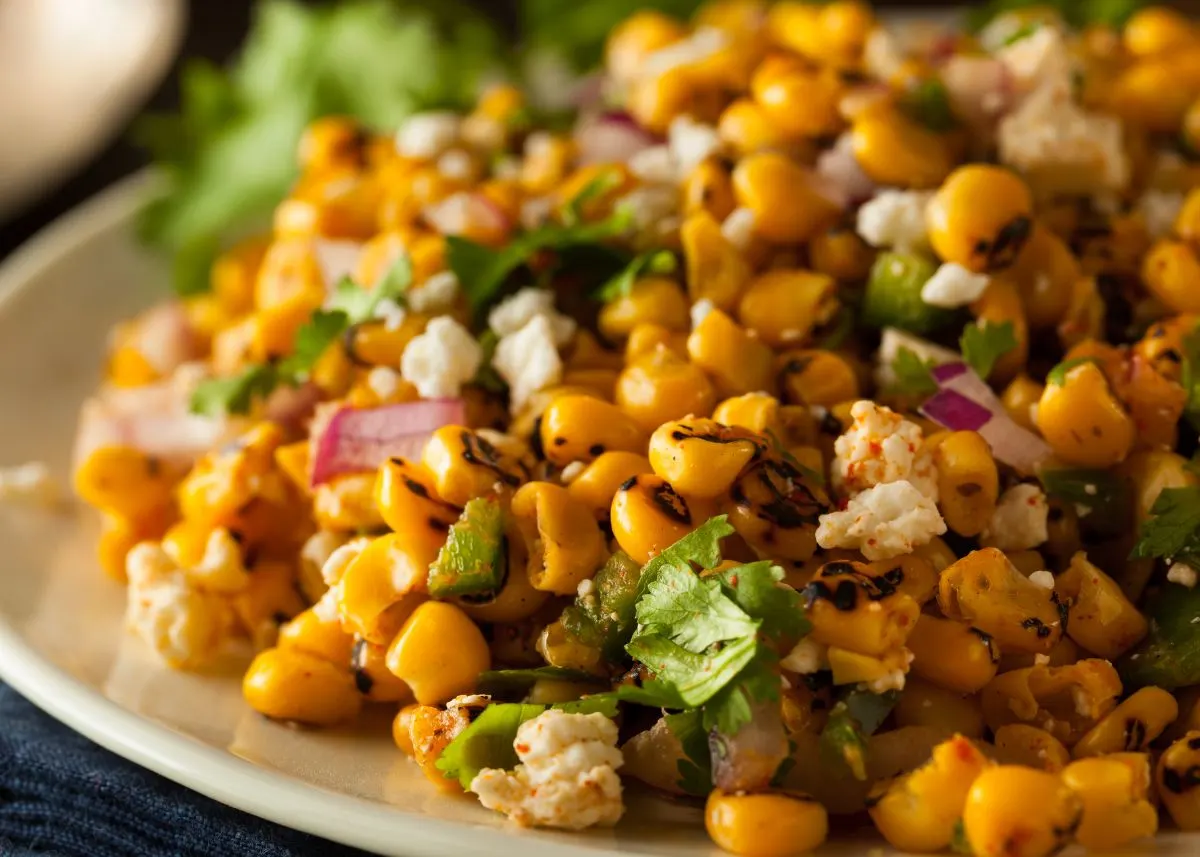 Corn salad with red onion, Mexican cheese, and cilantro on a plate.
