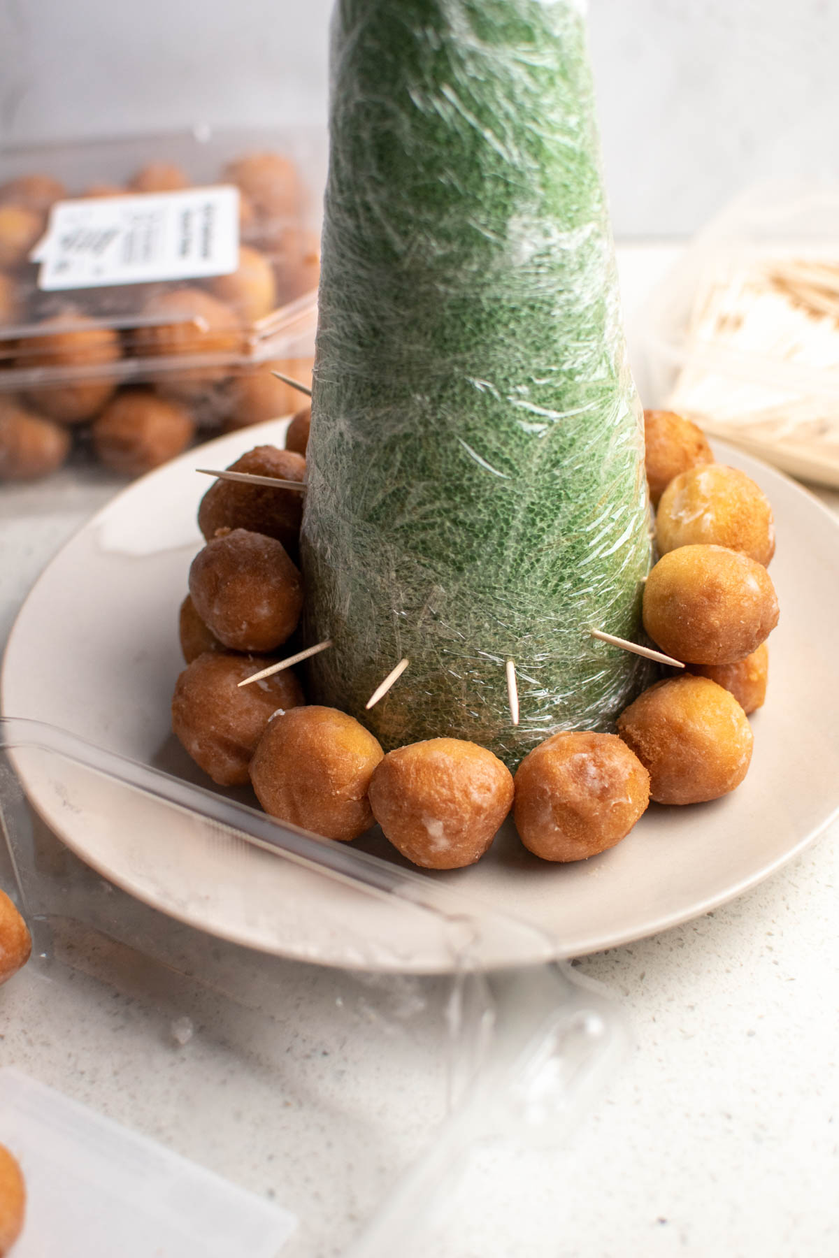 Donut holes on toothpicks sticking out of green styrofoam cone.