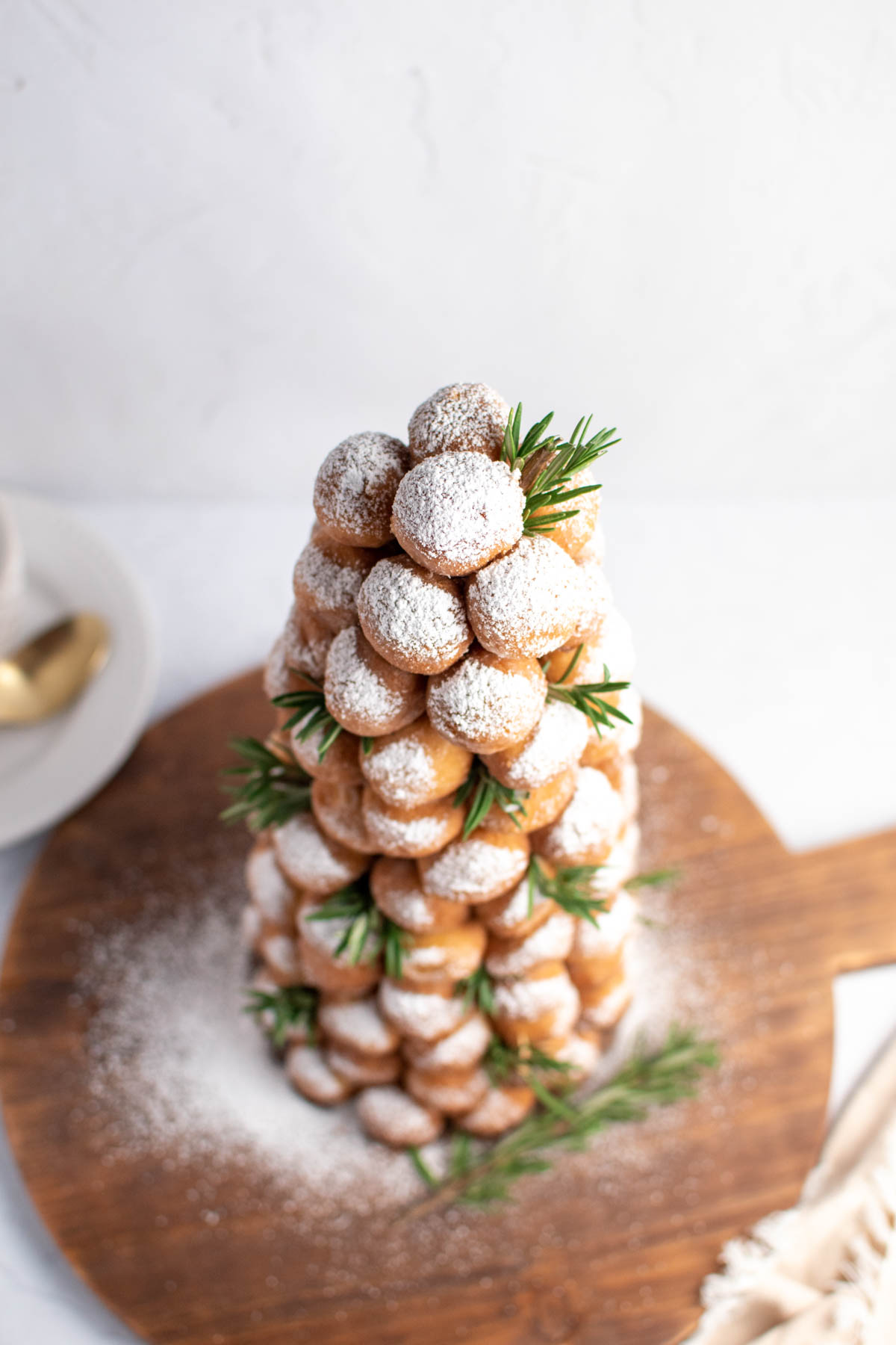 The top of a donut tree made with donut holes, powdered sugar, and fresh rosemary.