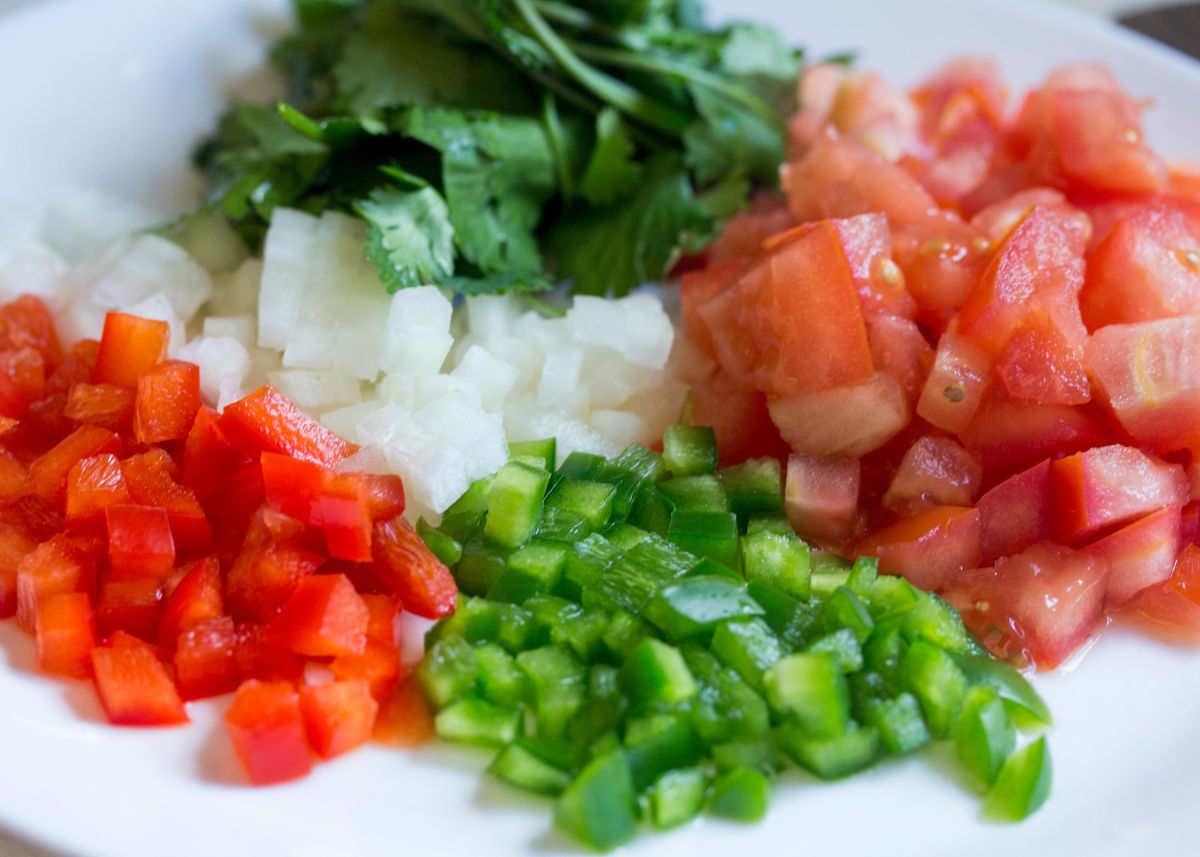 Fresh diced tomatoes, green chilies, cilantro, and onion on a white plate.