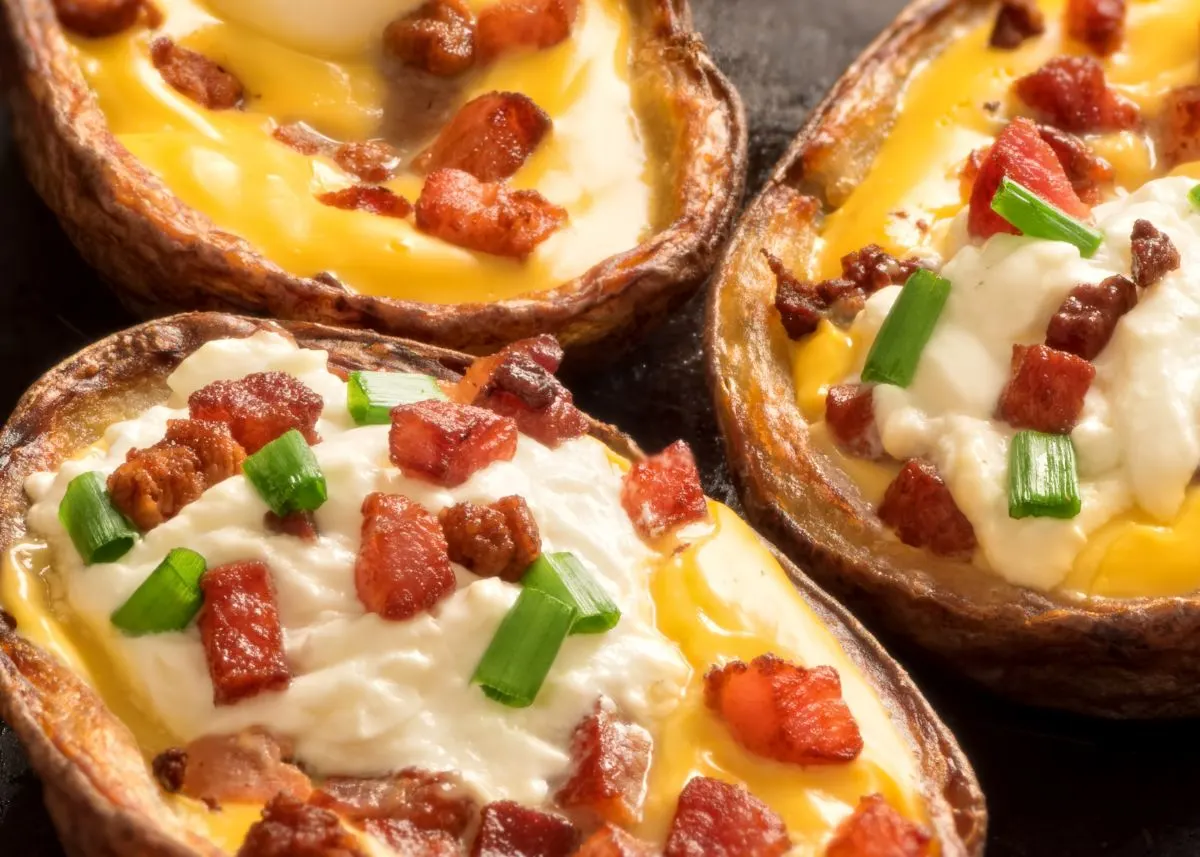 Close up of potato skins with bacon, sour cream, and green onion garnish.