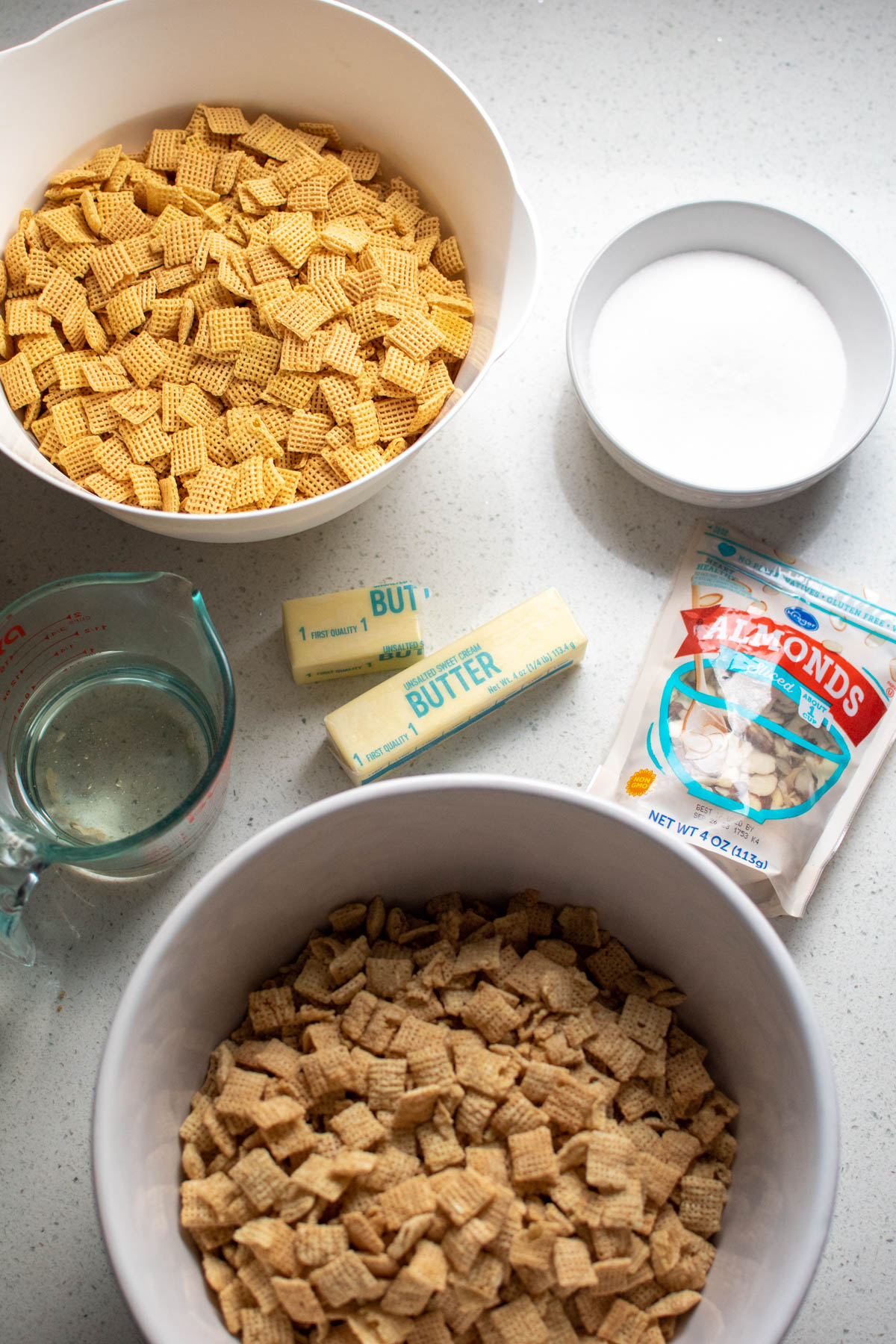 Sticky Chex mix ingredients on counter including butter, sugar, and almonds.
