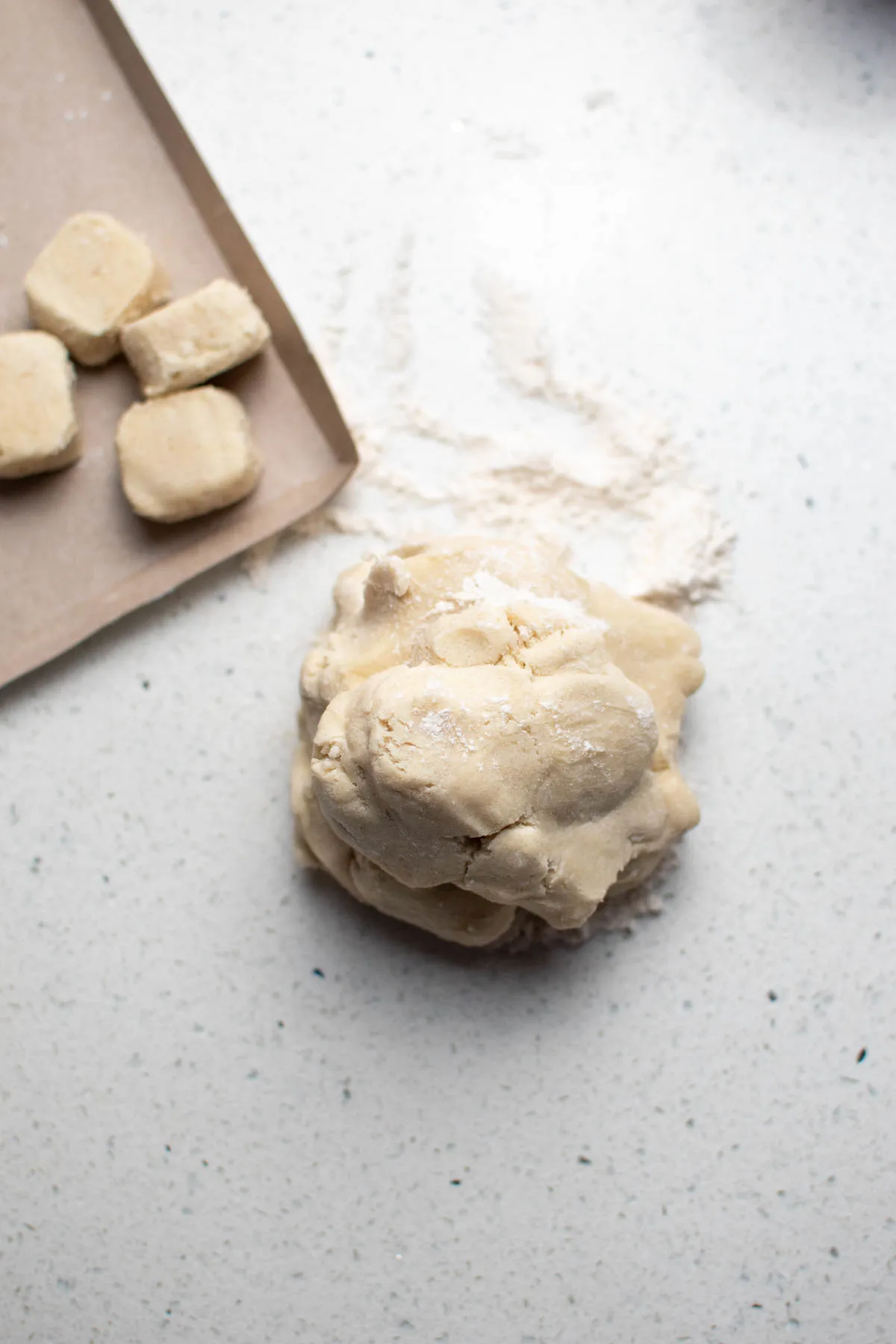 Large ball of sugar cookie dough and sprinkled flour on counter.