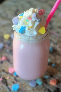 Conversation hearts strawberry hot chocolate with whipped cream and a pink straw.