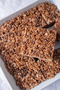 Chocolate Rice Krispie treats with chocolate chips in a white casserole baking dish.