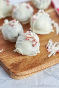 Several Oreo cookie balls covered in white chocolate with pink sprinkles.