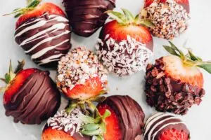 Close up image of vegan chocolate covered strawberries with chocolate drizzle and sprinkles.
