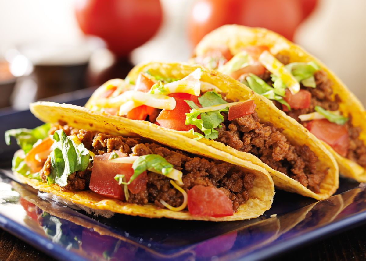 Hard shell tacos with ground beef, tomatoes and lettuce on a platter.
