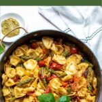 Pinterest graphic with text overlay and photo of black skillet full of basil pesto tortellini.