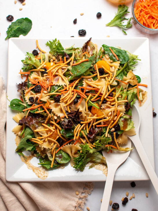 Asian bowtie pasta salad with chow mein noodles on white square platter.