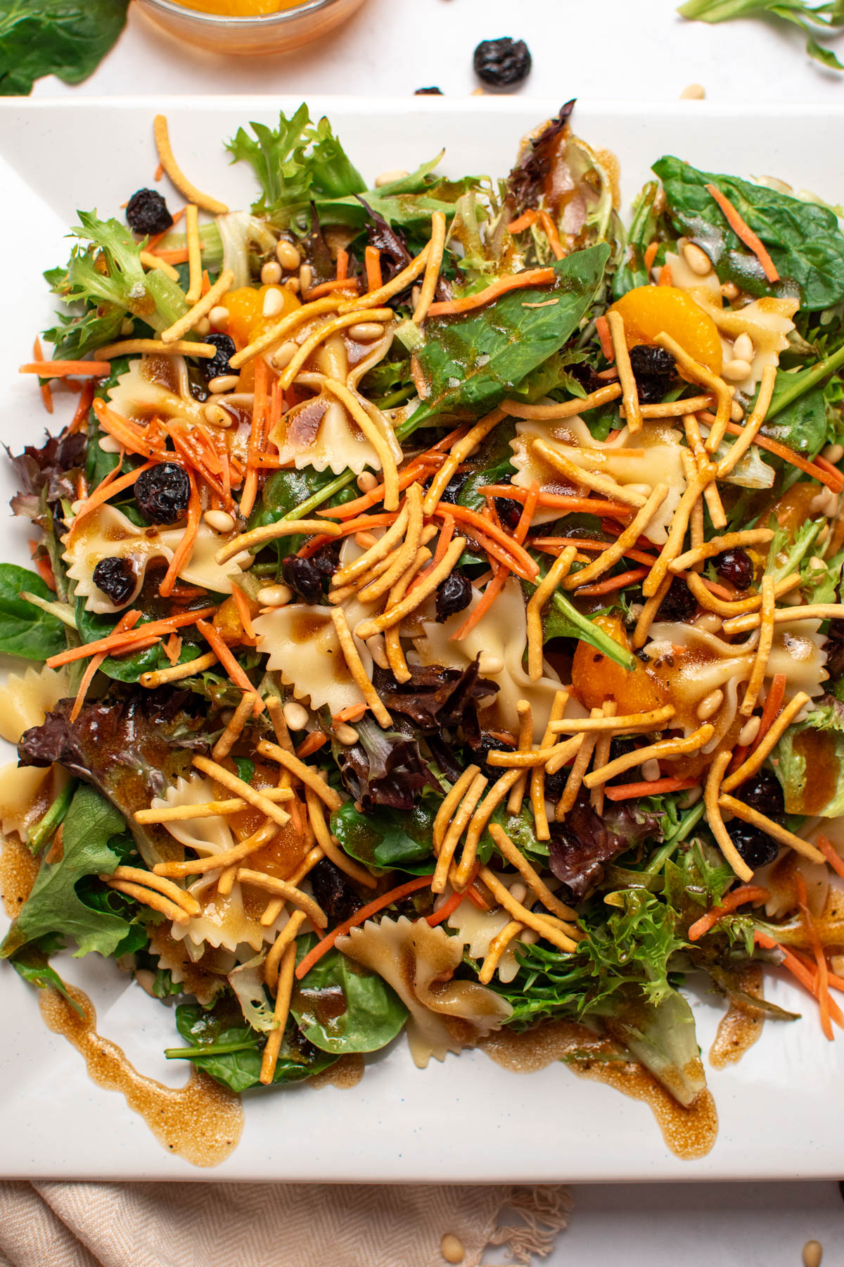 Asian bowtie pasta salad with spinach, chow mein noodles, oranges, and carrots.