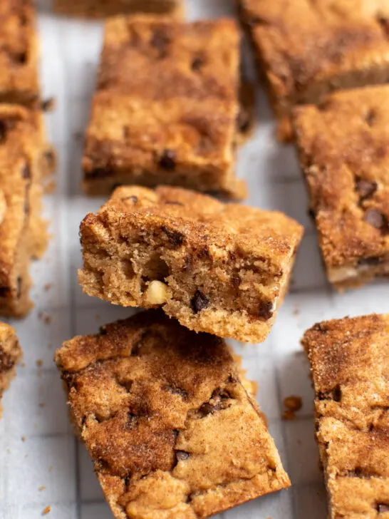 Group of cinnamon chocolate chip blondies on parchment paper with one blondie leaning on another.