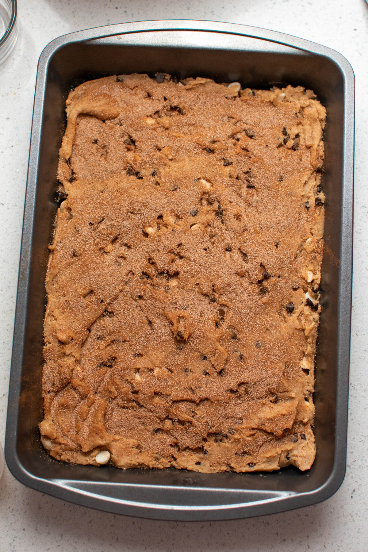 Metal pan of unbaked chocolate chip blondies on counter top.