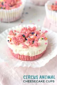 Pink and white mini cheesecake with sprinkles in a white cupcake liner.