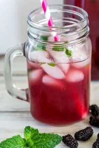 Mulberry iced tea in a mason jar with a pink and white striped straw.