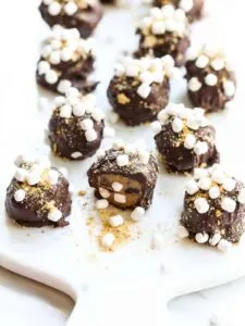 Smore cookie dough truffles with mini marshmallows on wood cutting board.