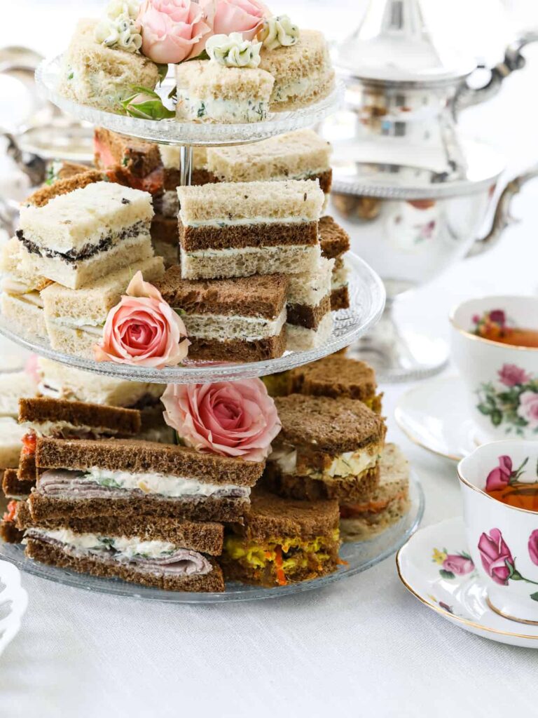 Tiered tray of different tea party sandwiches with brown and white bread.