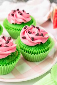 Watermelon cupcakes with pink frosting on plaid plate.