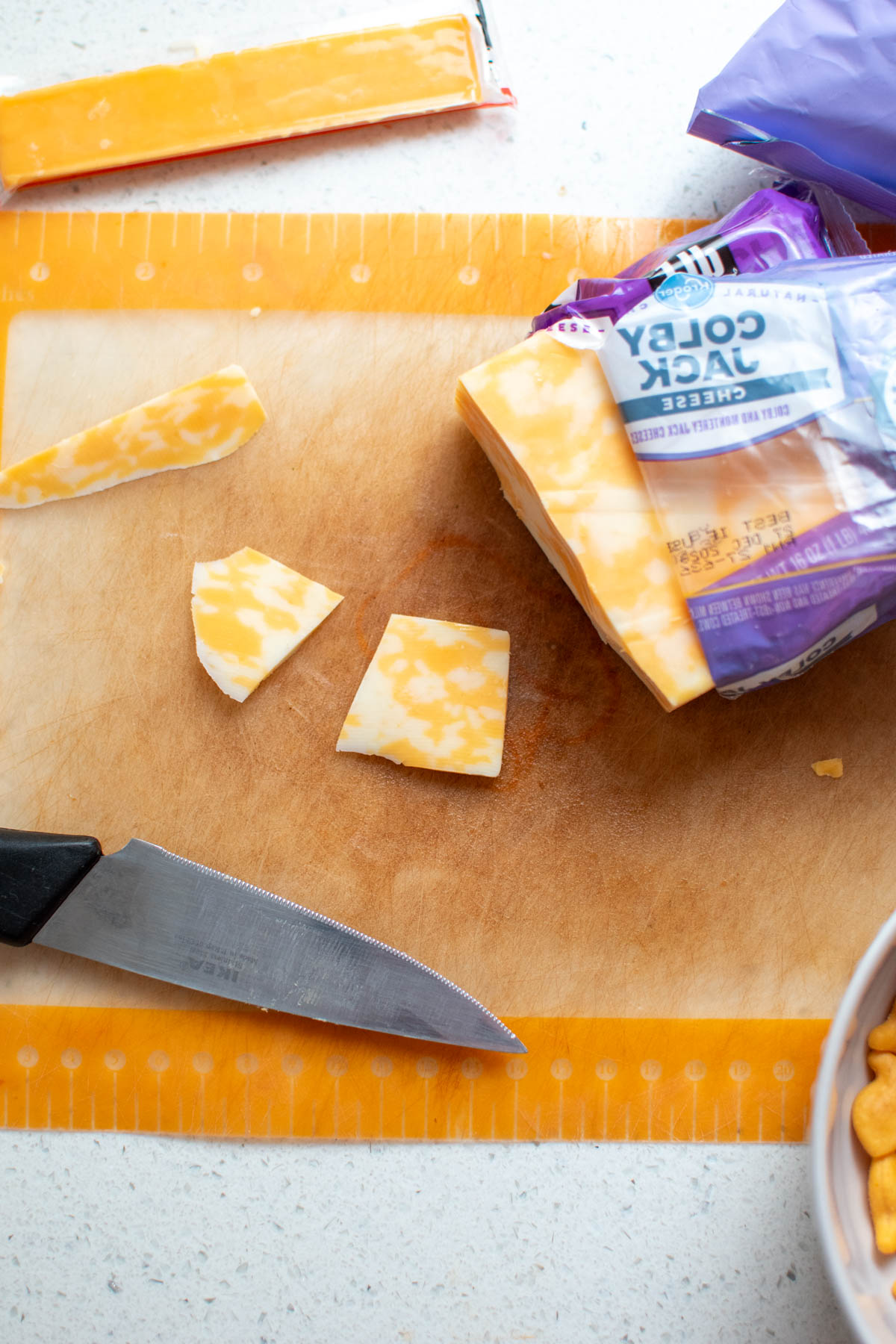 Slices of Colby Jack cheese on cutting board with knife nearby.