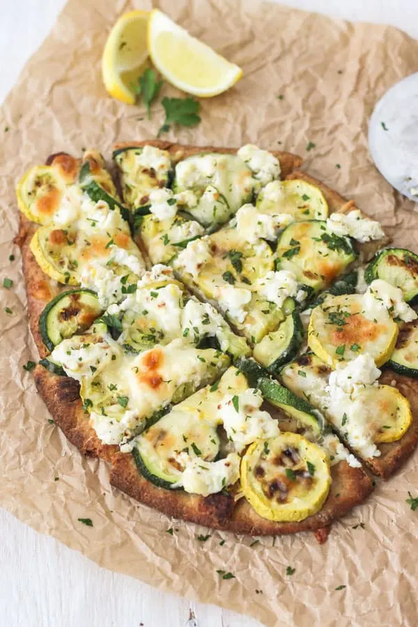 Sliced cheesy flatbread with yellow and green squash.