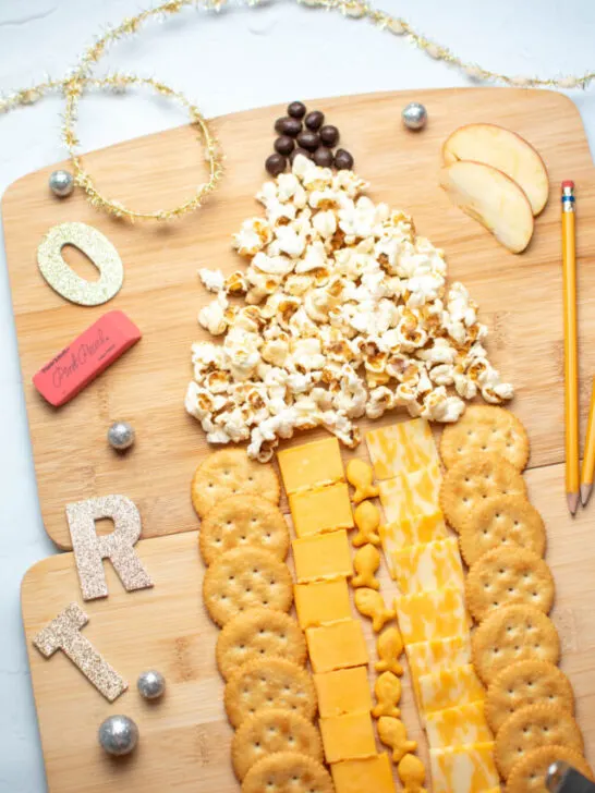 Back to school charcuterie board in the shape of a pencil with small school trinkets decorating.