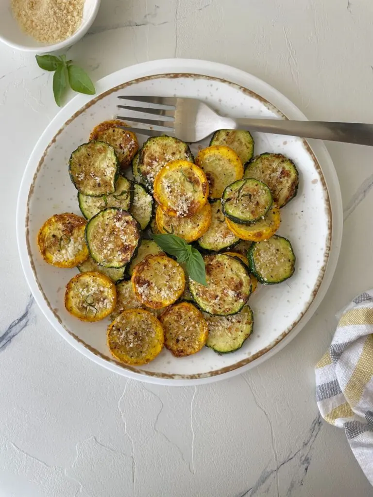 Cheesy, lightly fried summer squash on a white plate.