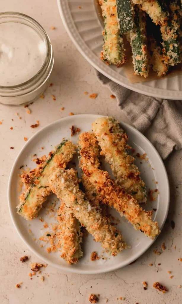 Zucchini fries with breadcrumb coating on a white plate.