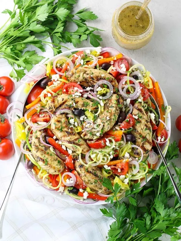 Greek salad with chicken, zucchini noodles, and peppers in a large serving bowl.