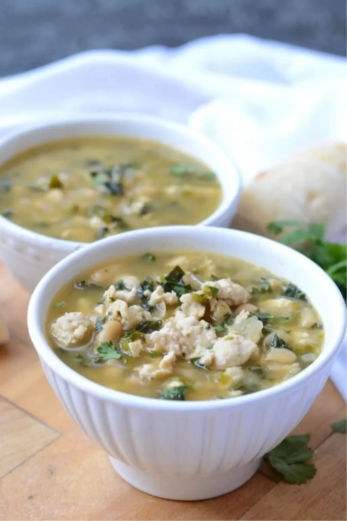 White turkey chili with white beans and poblano peppers in two white bowls.