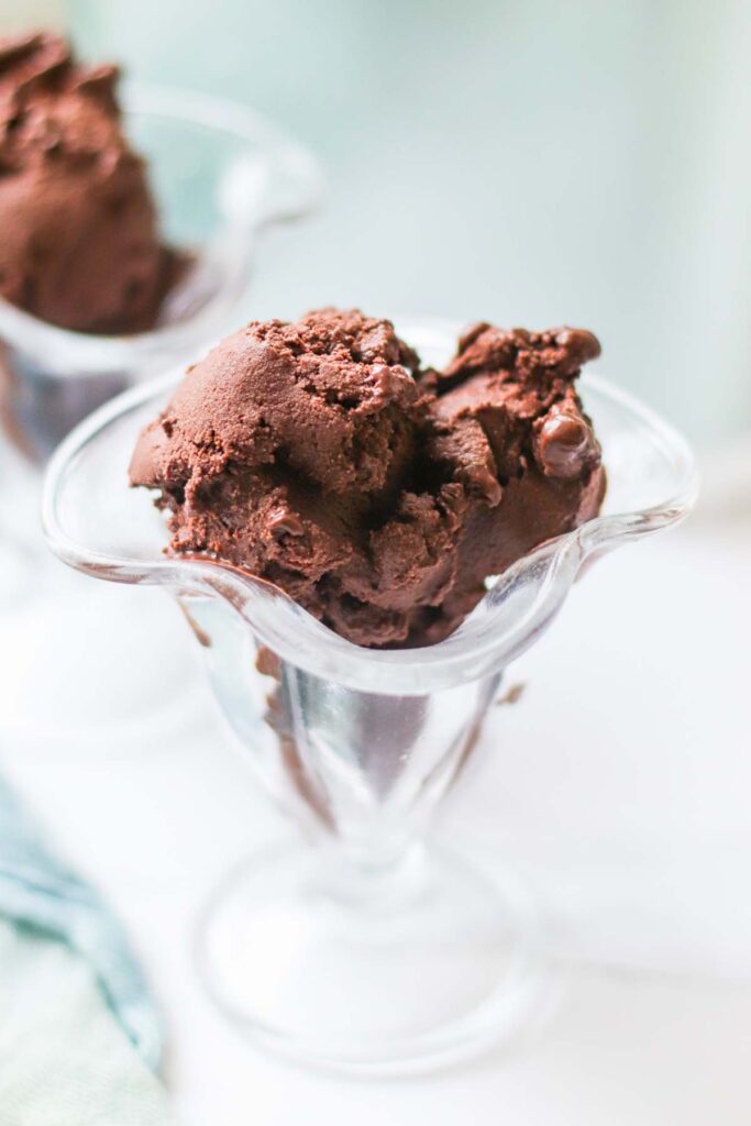 A clear glass ice cream serving vessel with chocolate sorbet.