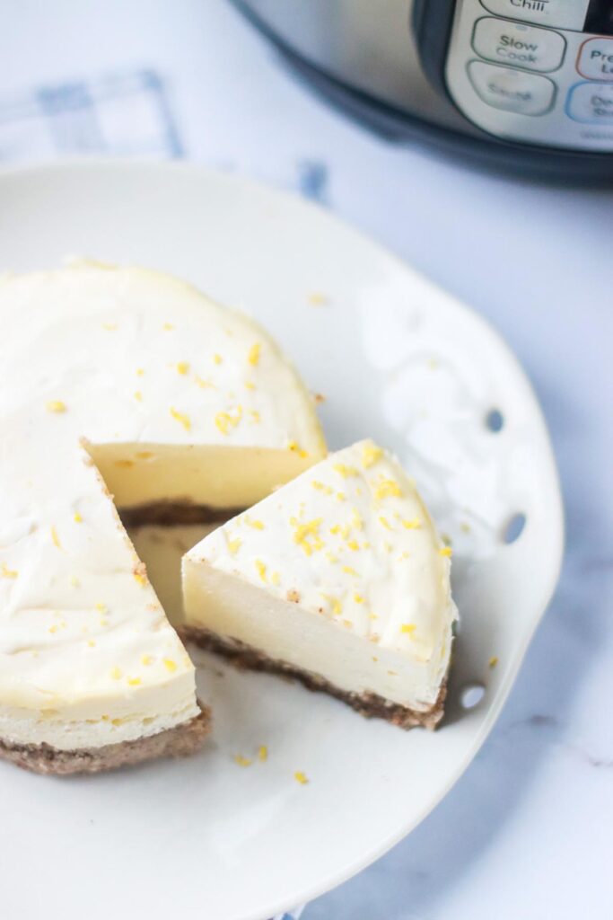 A round keto cheesecake with a sliced slide to the side on a serving platter.