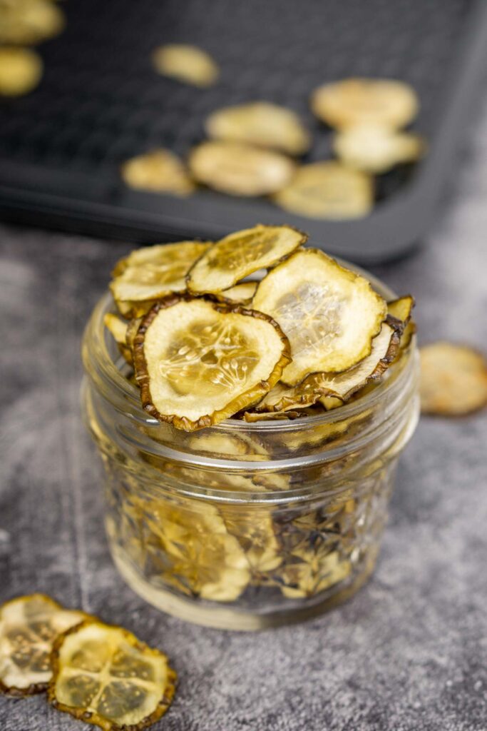 Dehydrated pickle chips in a short mason glass jar.