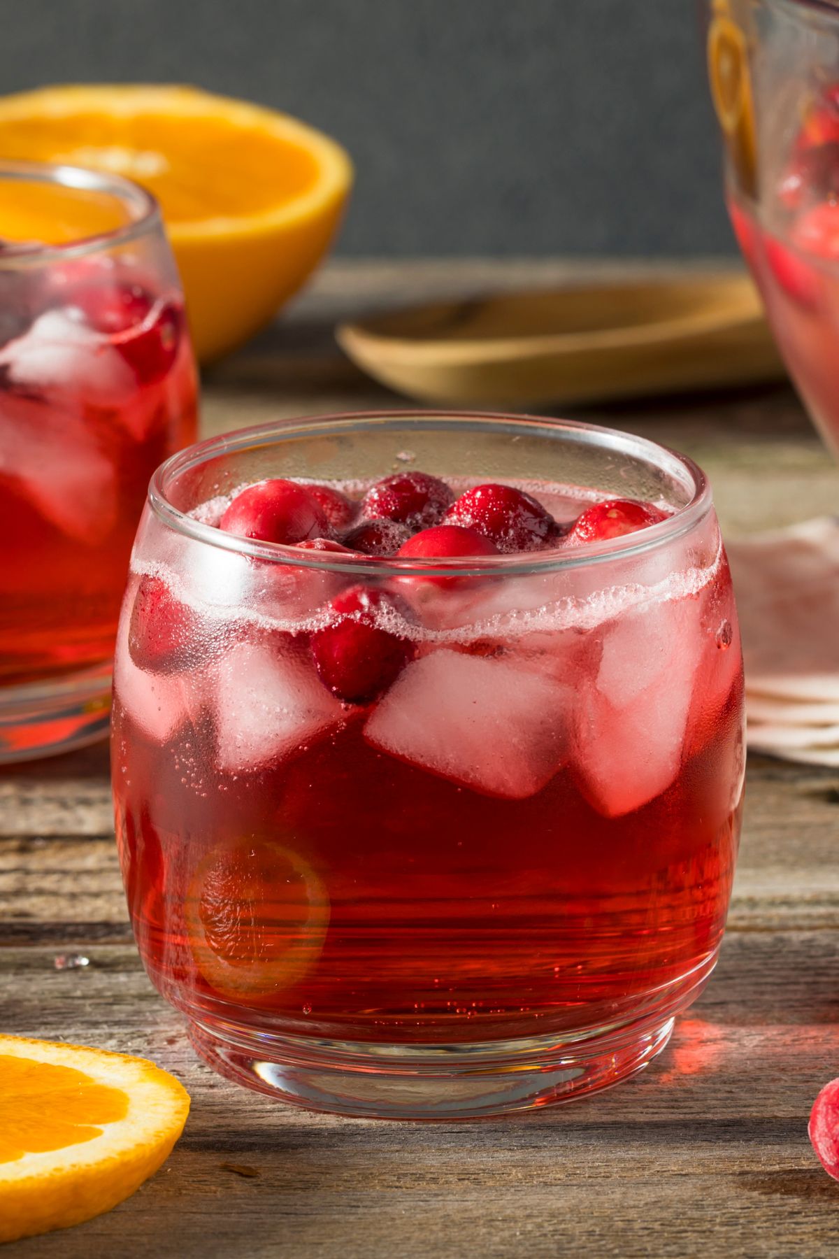 Cranberry mocktail in a short clear glass with orange wedges.