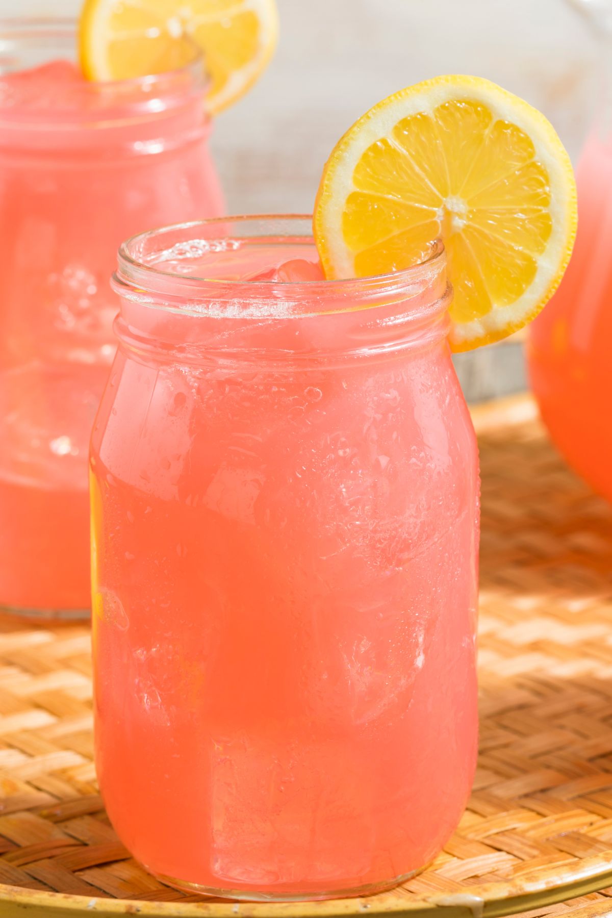 Pink lemonade in mason glass jars with a lemon slice garnish.