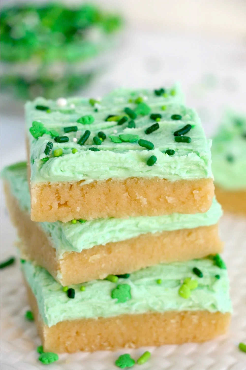 A stack of sugar cookies bars with green icing and sprinkles.