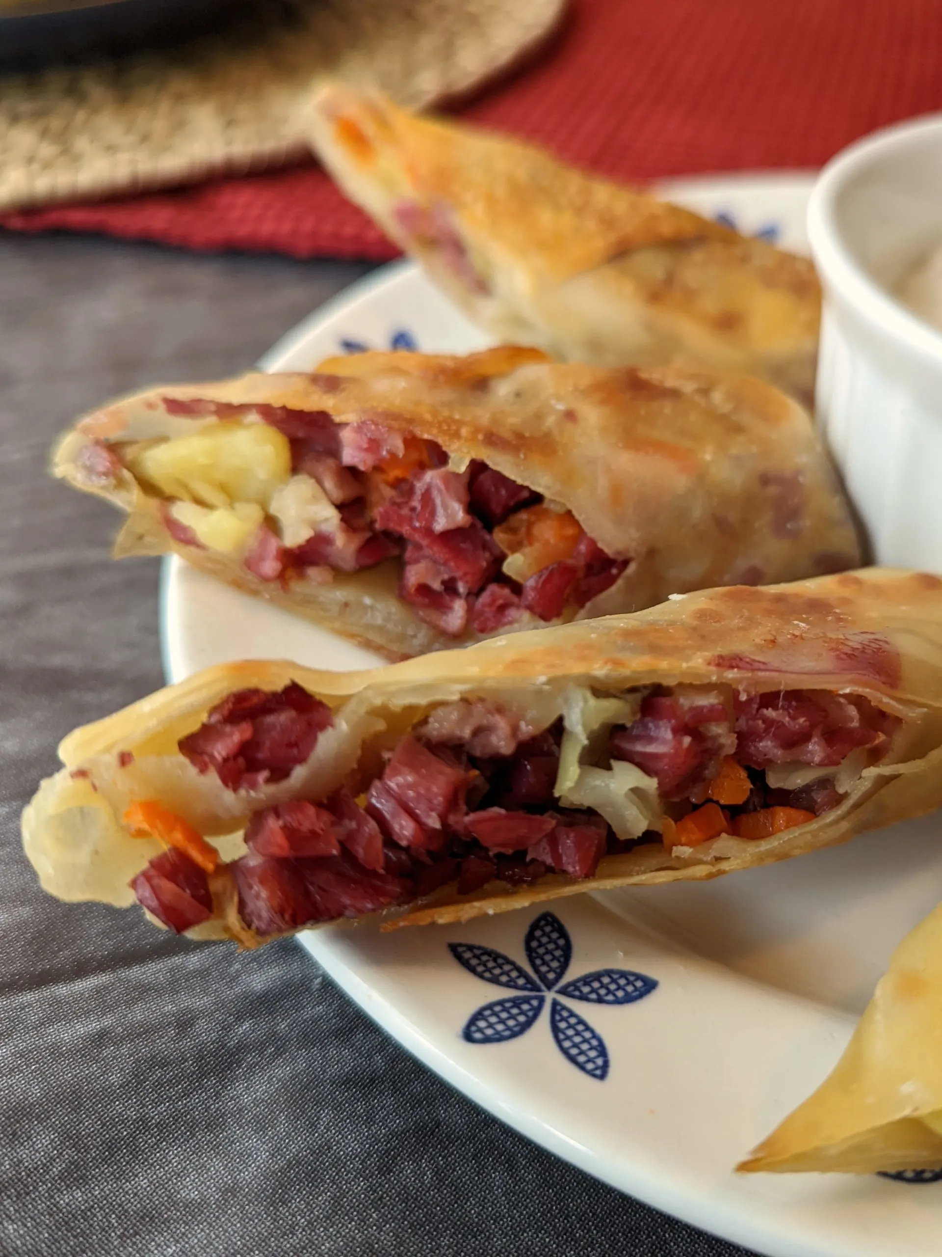 Corned beef and cabbage egg rolls on a plate with dipping sauce bowl.