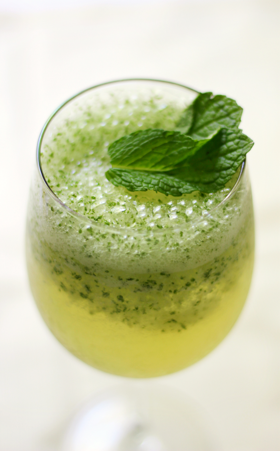 Green tea mocktail in a clear glass with mint garnish.