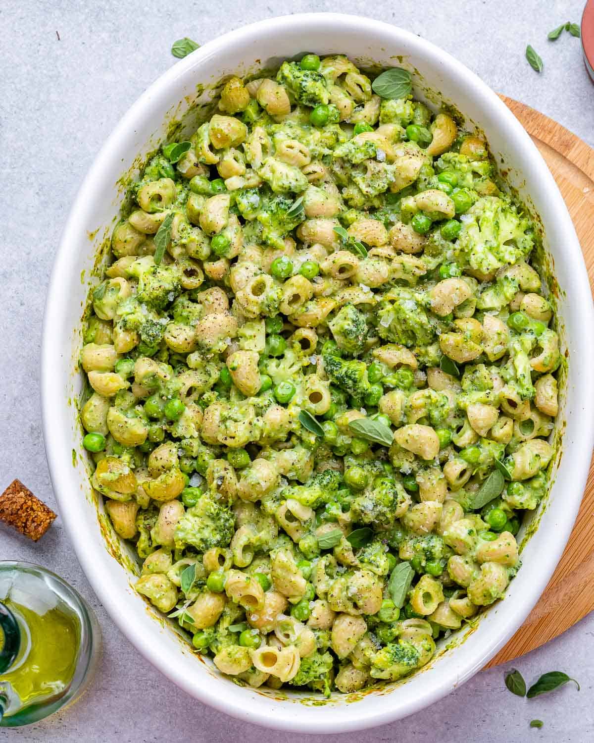 Macaroni and cheese with healthy greens in a large white serving dish.
