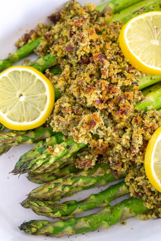 Roasted asparagus with a crispy topping and lemon slices on top.
