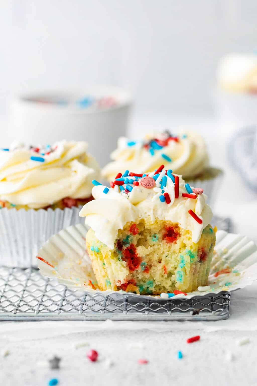 Funfetti cupcakes with white frosting and red and white sprinkles.