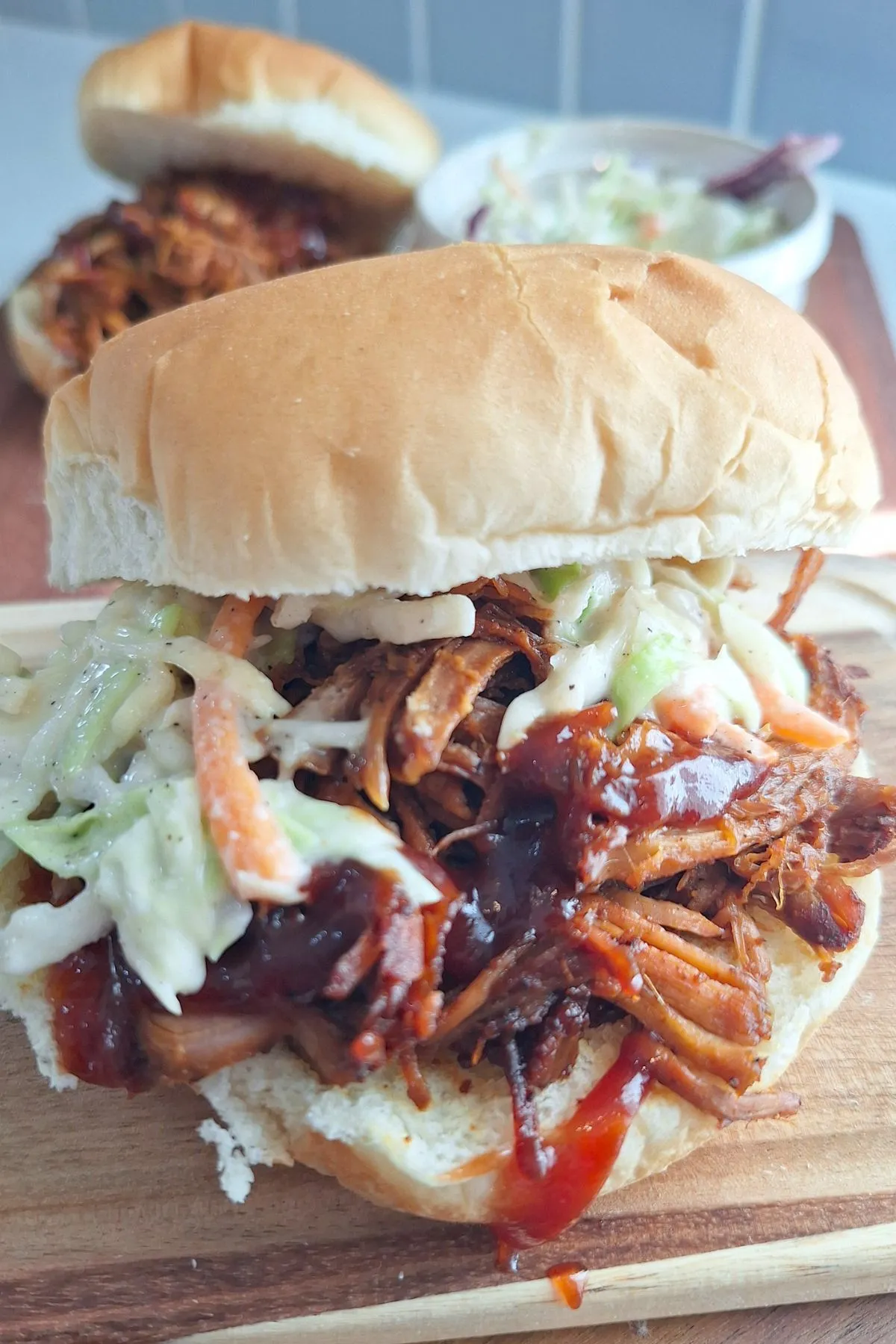 A pulled pork sandwich with green cabbage and a mini American flag.